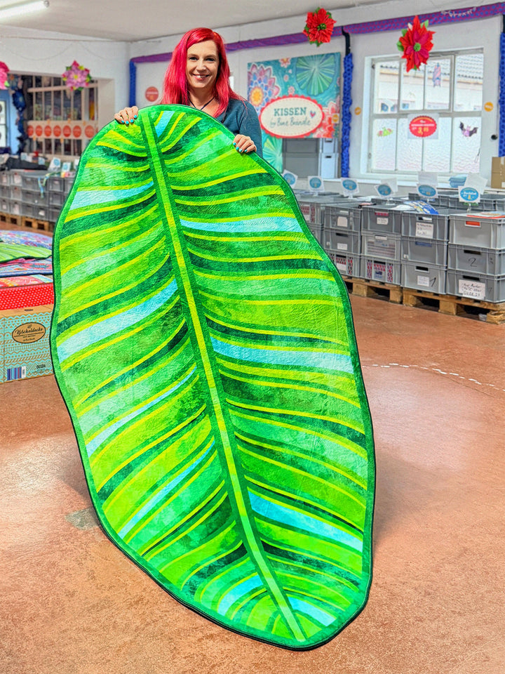 Superweicher Teppich im Design von Bine Brändle in Form eines Bananenblatts mit Motiv in verschiedenen Grüntönen, tropisch und modern gestaltet.