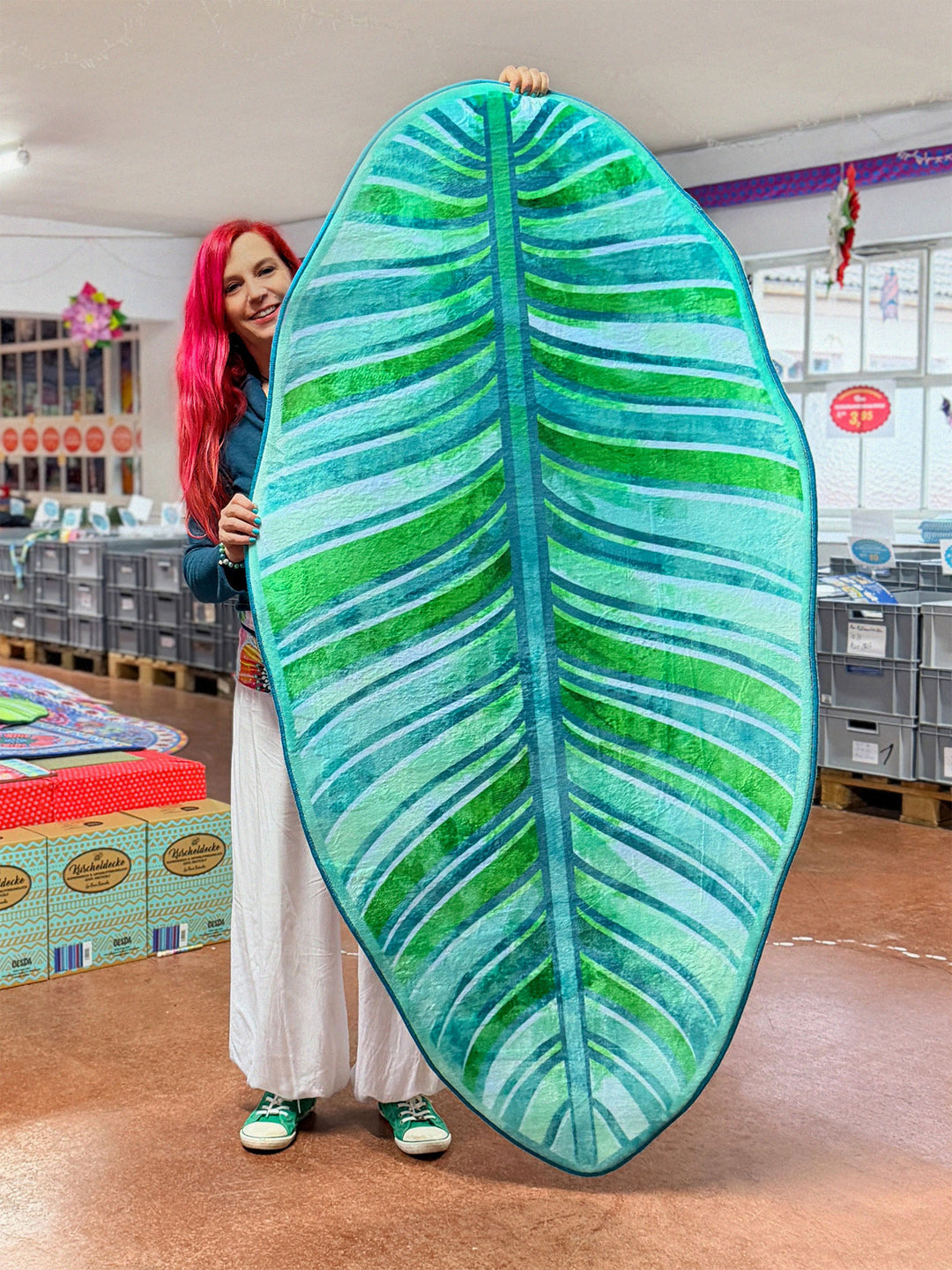 Superweicher Teppich im Design von Bine Brändle in Form eines Bananenblatts mit Motiv in Türkis und Grün, tropisch und modern gestaltet.