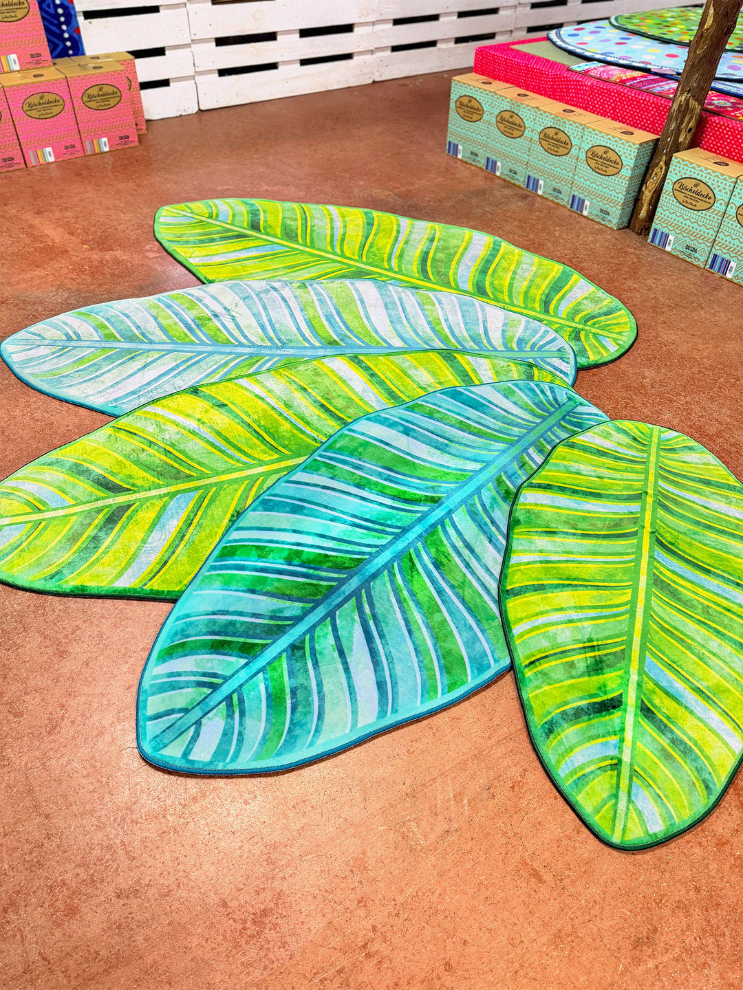 Superweicher Teppich im Design von Bine Brändle in Form eines Bananenblatts mit Motiv in Türkis und Grün, tropisch und modern gestaltet.
