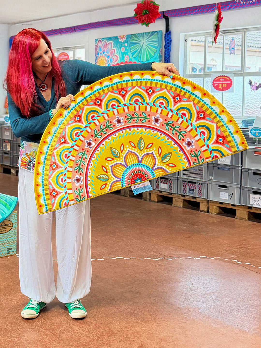 Superweiche Kuschelmatte im Design von Bine Brändle in halbrunder Form mit farbenfrohem Mandala-Bogen in Gelb, Türkis, Rosa und Rot, dekorativ und freundlich gestaltet.
