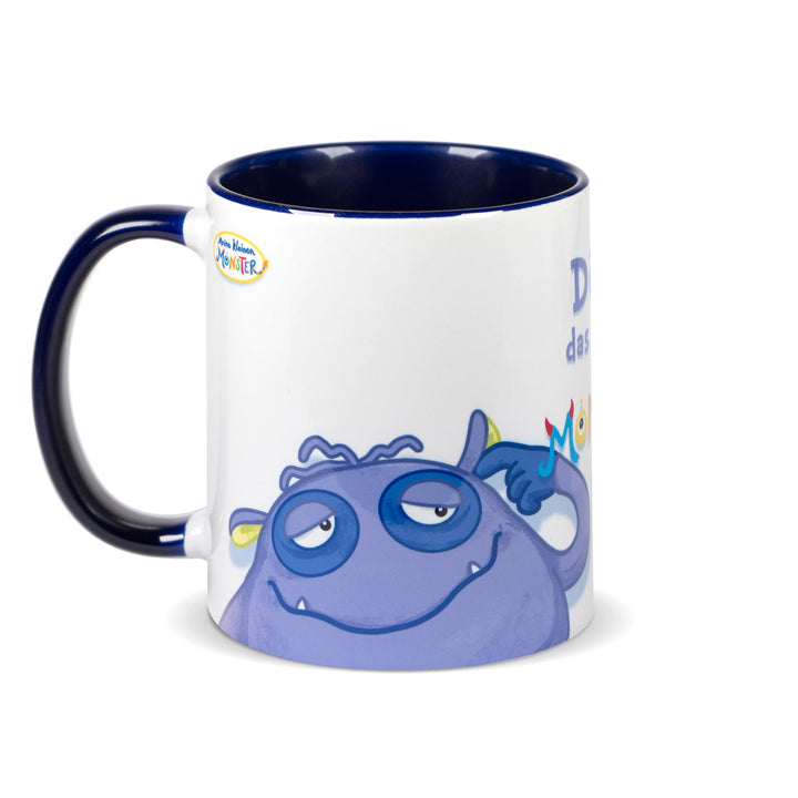 Keramiktasse mit dunkelblauem Henkel und dunkelblauem Innenrand, bedruckt mit dem müden Monster „Dösi“ in Blau- und Lilatönen.